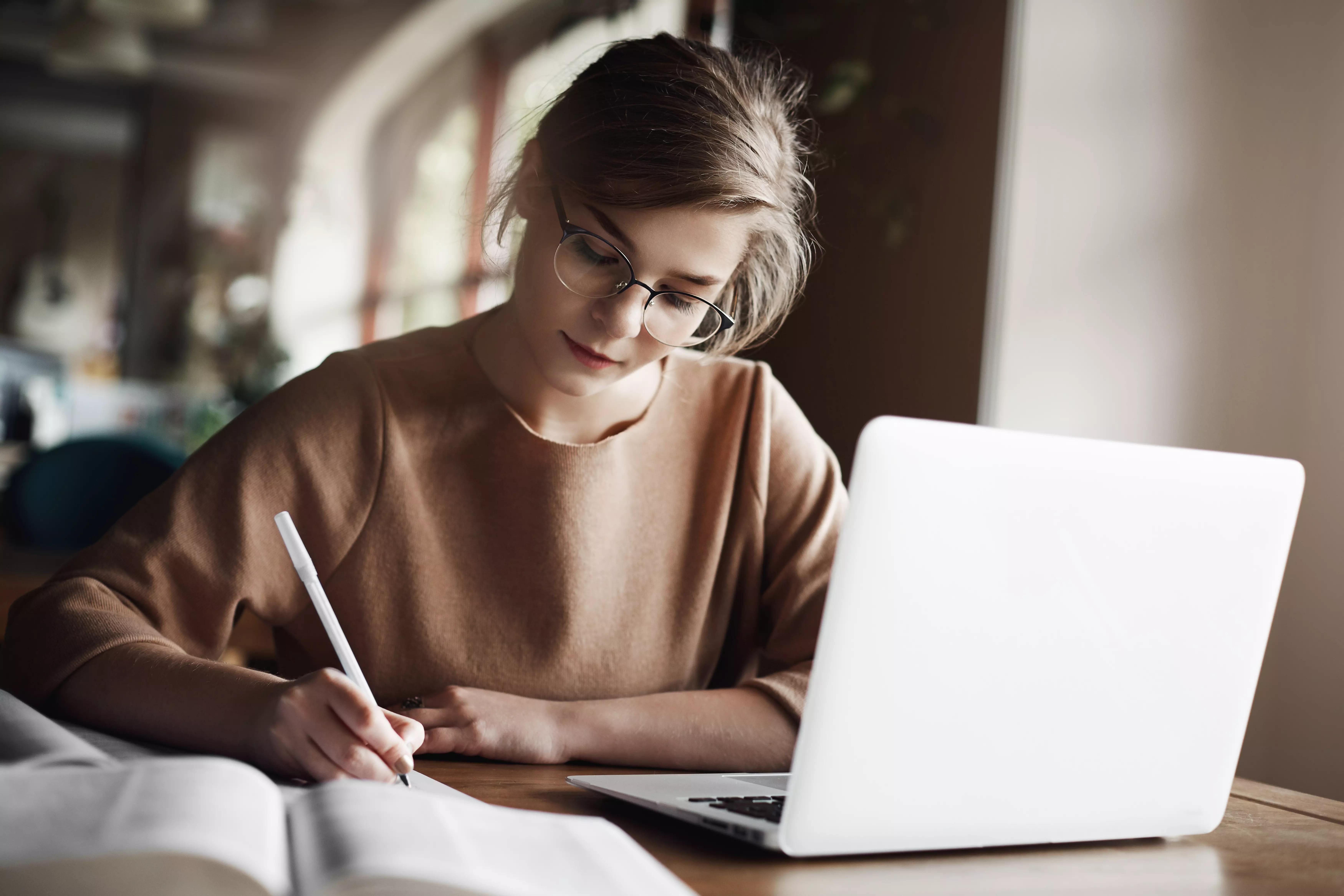 AnyConv.com__hardworking-focused-woman-trendy-glasses-concentrating-writing-essay-sitting-cozy-cafe-near-laptop-working-making-notes-carefully продвижение онлайн школы