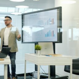 Man presenting data on a large screen to colleagues