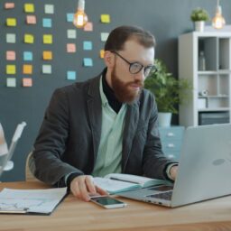 Man working on laptop in modern office with sticky notes