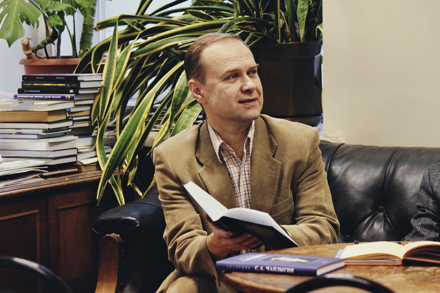 man holding book while sitting on black leather couch