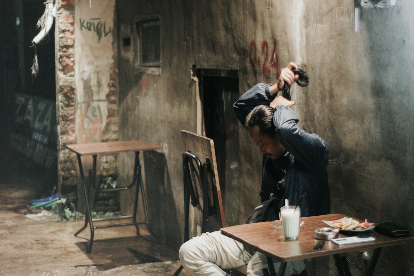 a man sitting at a table in an alleyway